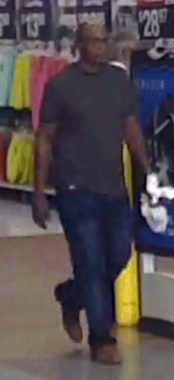Photo of suspect at Wal-Mart. Suspect is wearing black framed glasses, dark colored shirt with jeans and brown shoes.